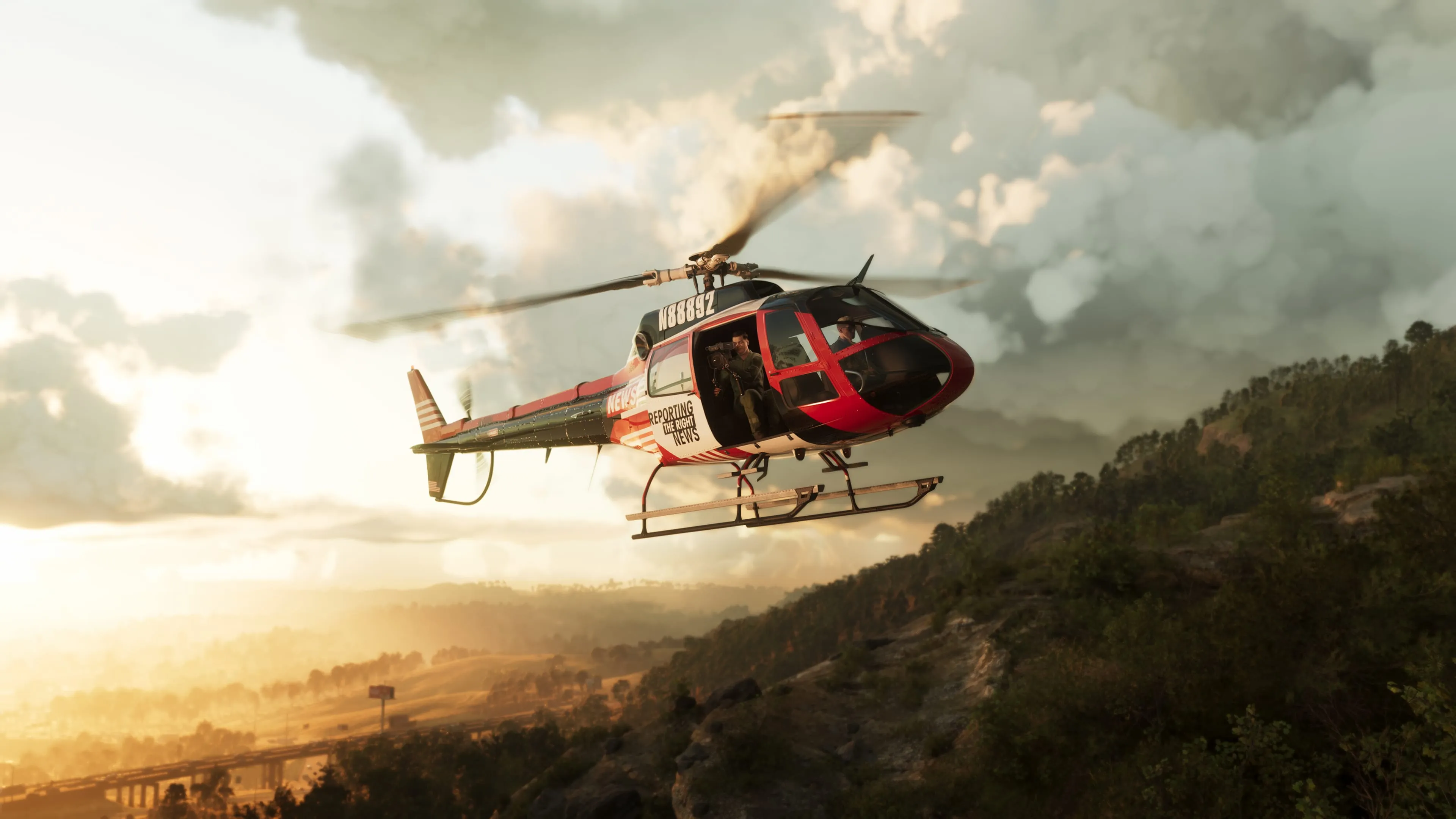 A red and white news helicopter flying alongside a forested ridge in Mount Kalaga National Park at sunset, with wooded hills and a distant highway in the hazy valley below. Official Rockstar Games screenshot.