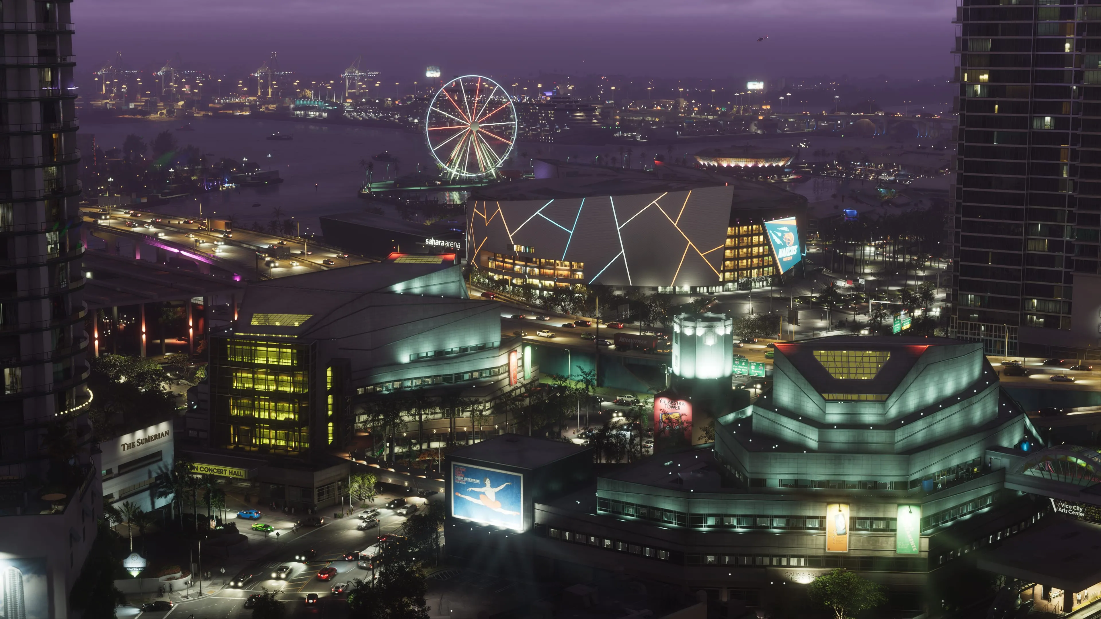 The Vice City skyline at night in GTA 6, looking down over lit arts-district blocks and traffic toward a waterfront ferris wheel, with port cranes across the bay behind it. Official Rockstar Games screenshot.